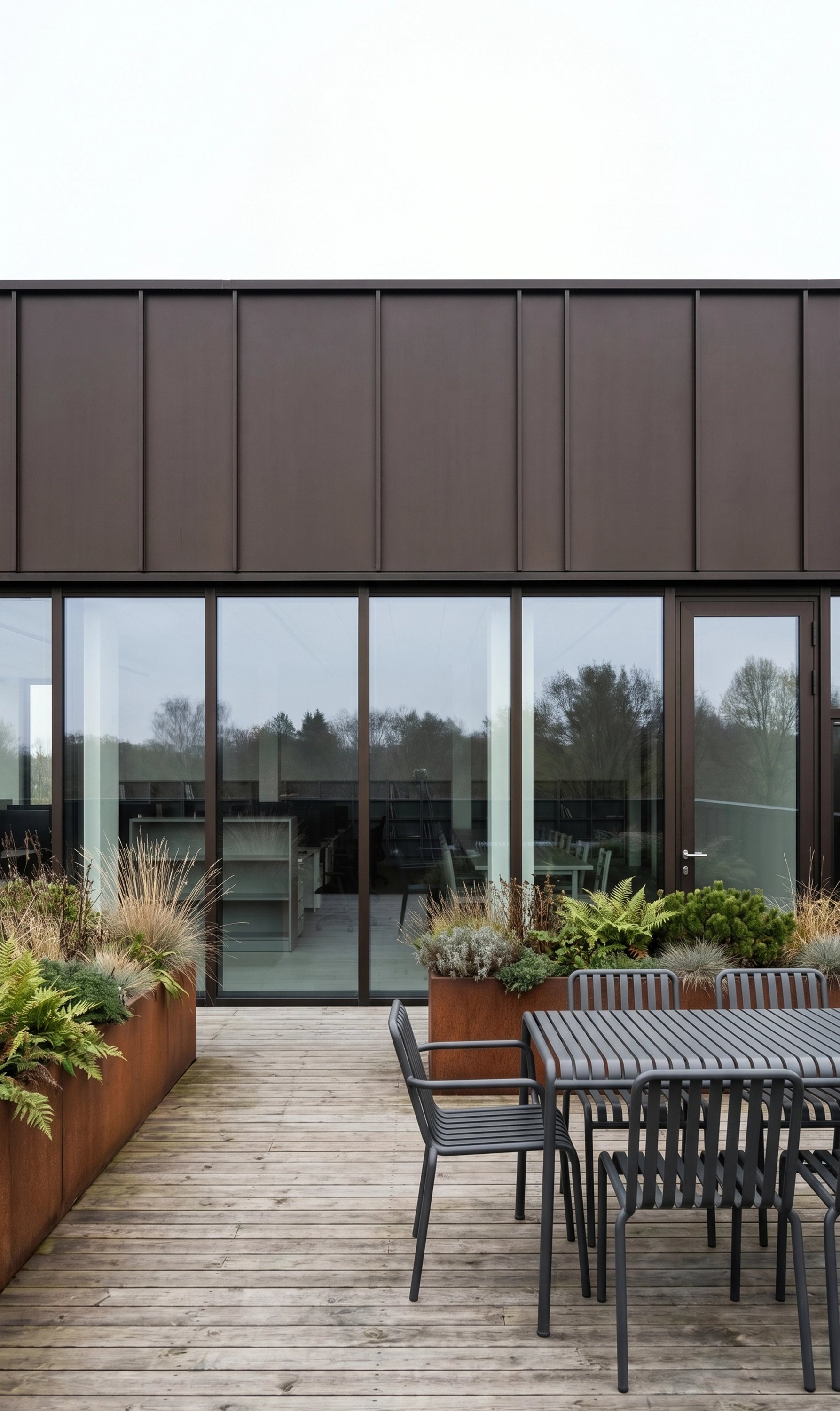 Timber roof terrace of the Cube building, with planters and outdoor furniture against dark metal cladding.